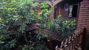 A traditional building with brick walls and a tiled roof, surrounded by lush greenery. - RedDoorz near Stasiun Kota Baru Malang (Malang)