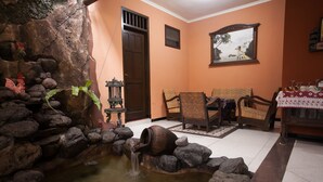A room with a stone fountain, wooden furniture, and a door. - RedDoorz near Stasiun Kota Baru Malang (Malang)