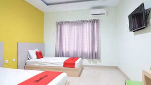 A hotel room with two beds, a TV, an air conditioning unit, and a window with curtains. - RedDoorz near Museum Keraton Surakarta (Surakarta)