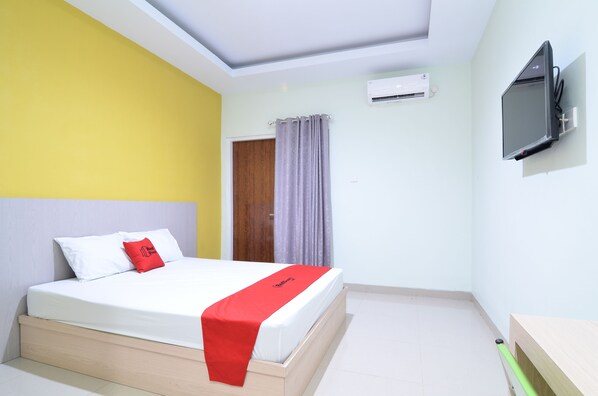 A hotel room with a bed, a TV mounted on the wall, and an air conditioning unit. - RedDoorz near Museum Keraton Surakarta (Surakarta)