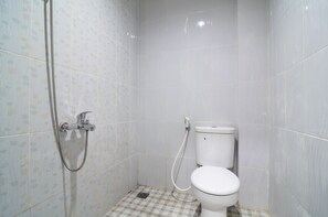 A small, tiled bathroom with a shower, toilet, and checkered floor. - RedDoorz near Museum Keraton Surakarta (Surakarta)
