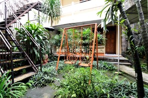A courtyard with a staircase, swing set, and lush greenery.