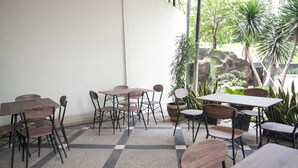 Un patio interior con mesas y sillas, piso de cuadros y plantas en macetas.
