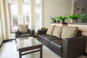 Una sala de estar con una mesa de centro de vidrio, dos sofás y plantas en macetas.