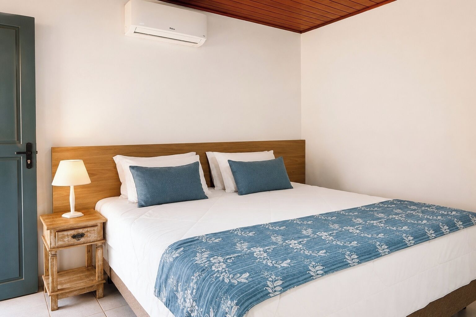 Ein Hotelzimmer mit Bett, Nachttisch, Lampe und Klimaanlage.