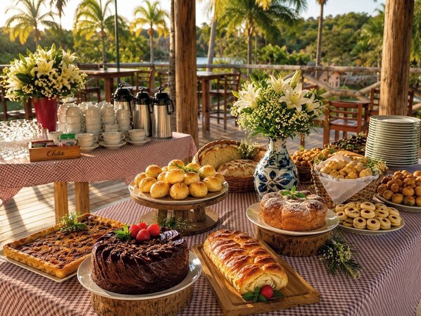 Una mesa de buffet con diversas opciones de repostería, un pastel de chocolate y un centro de mesa floral.