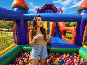 A person standing in front of a colorful inflatable play structure with a ball pit. - Hotel Fazenda Menino da Porteira (Ouro Fino)