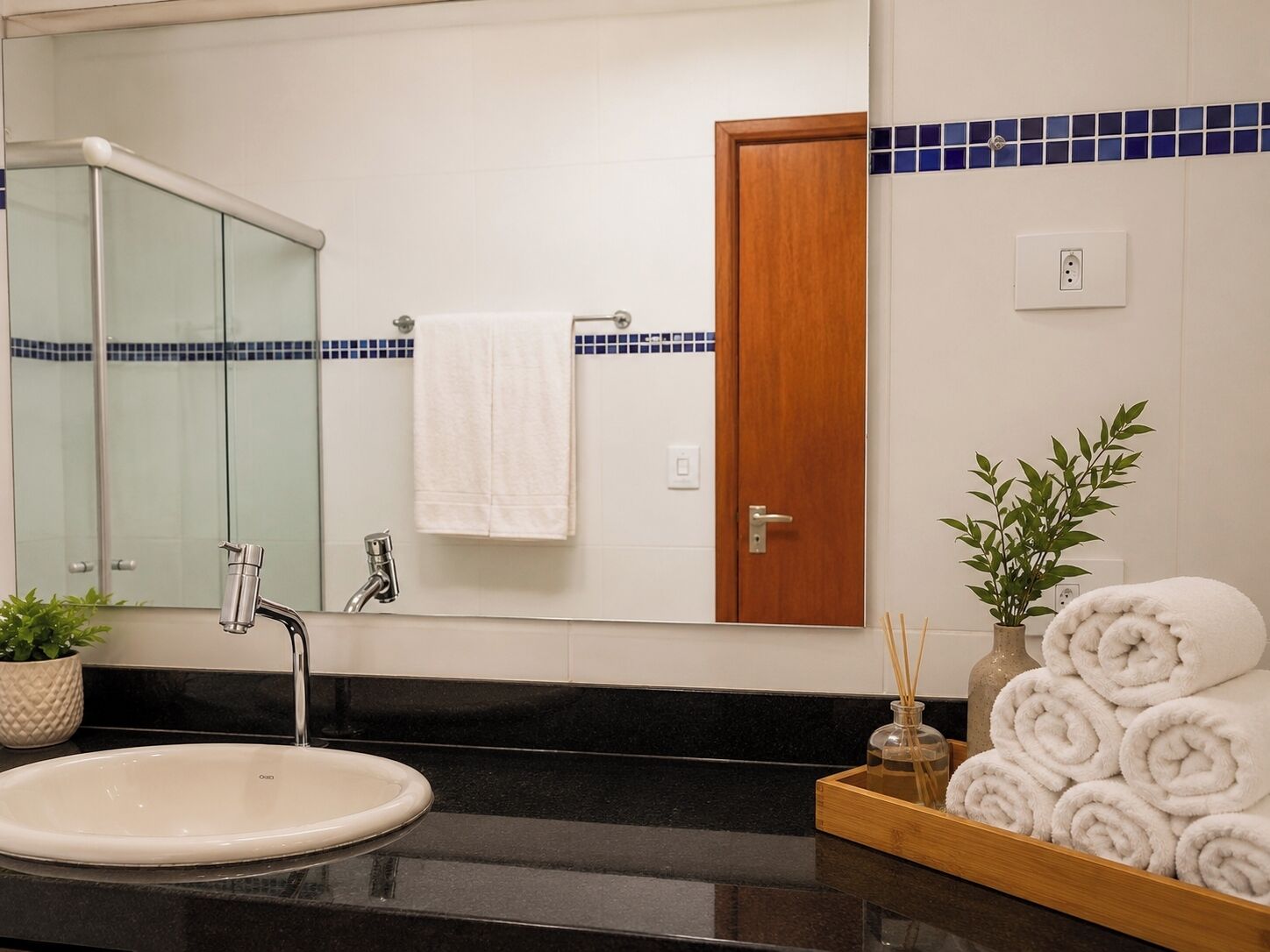 A bathroom with a sink, mirror, towel rack, and a door.