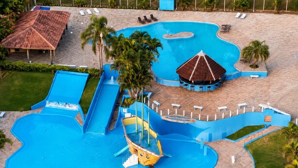 A large swimming pool with multiple slides and a small boat. - Hotel Fazenda Menino da Porteira (Ouro Fino)