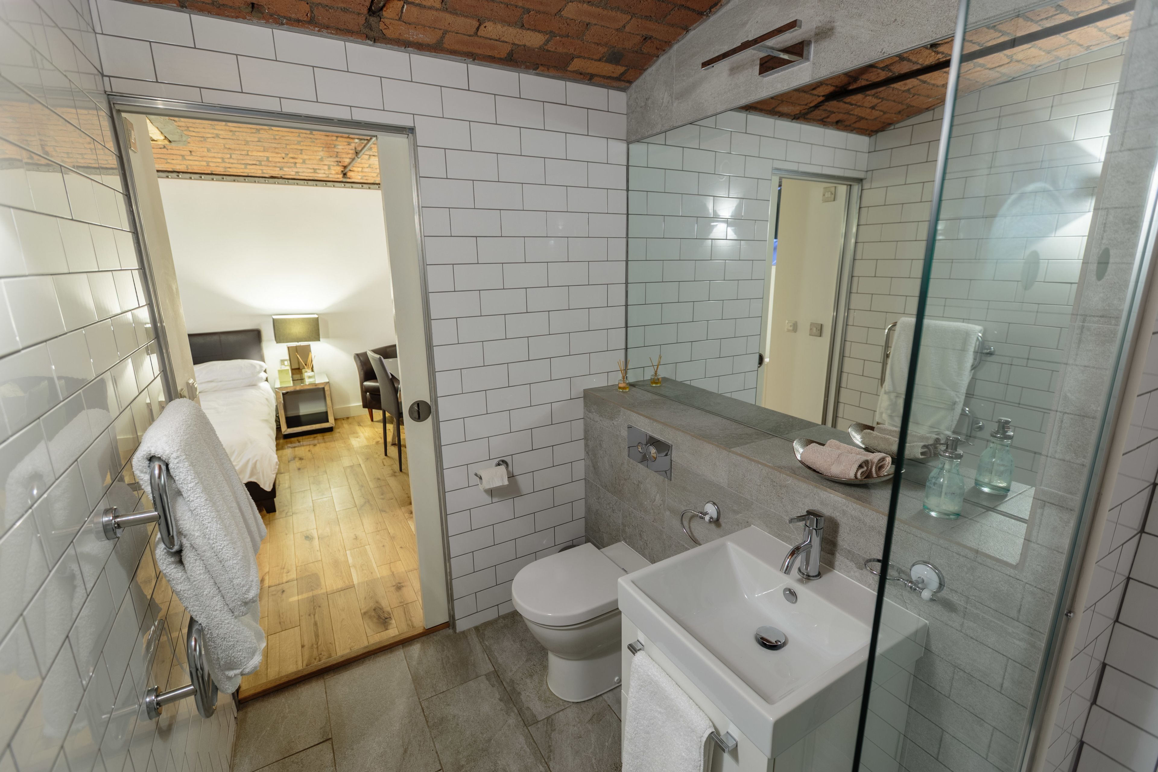 A modern bathroom with a glass shower enclosure, a white sink, and a toilet.