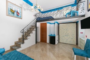 Amplia sala de estar con escalera, un sofá azul y una pequeña mesa.