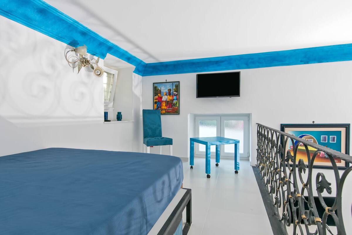 Un dormitorio con cama, una silla, una mesa y un televisor.