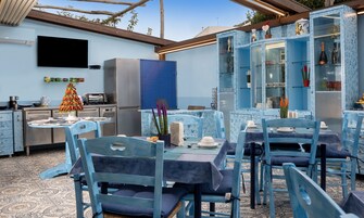 Un comedor con mobiliario azul y una cocina con televisión y electrodomésticos.