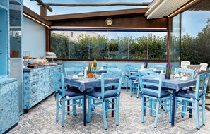 Comedor con mobiliario azul y vistas a zonas verdes a través de amplios ventanales.