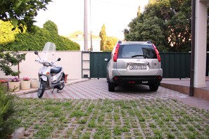A paved driveway with a parked scooter and a car.