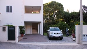 Un edificio moderno de dos pisos con un porche cubierto y un coche estacionado al frente.
