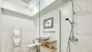 A modern bathroom with a glass shower enclosure, a toilet, a sink with a mirror above it, and a towel rack. - Maresía Canteras Urban (Las Palmas de Gran Canaria)