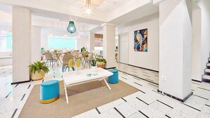 A modern hotel lobby with a dining area, a staircase, and a large abstract painting on the wall. - Maresía Canteras Urban (Las Palmas de Gran Canaria)