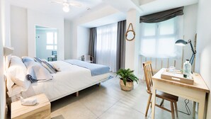 A modern bedroom with a bed, bedside table, desk, chair, and a potted plant. - Maresía Canteras Urban (Las Palmas de Gran Canaria)