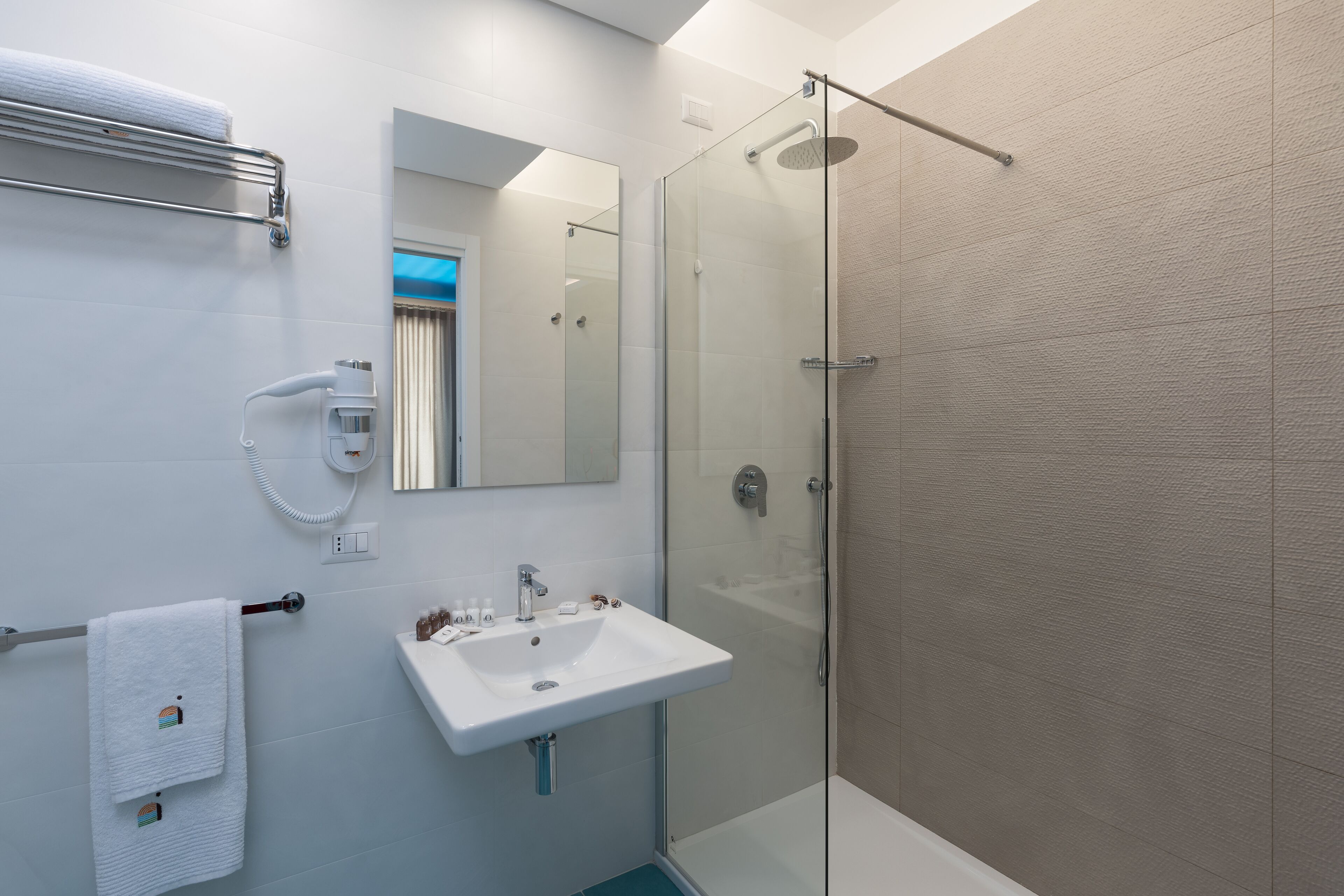 A modern bathroom with a glass-enclosed shower, a white sink, and a mirror above it.