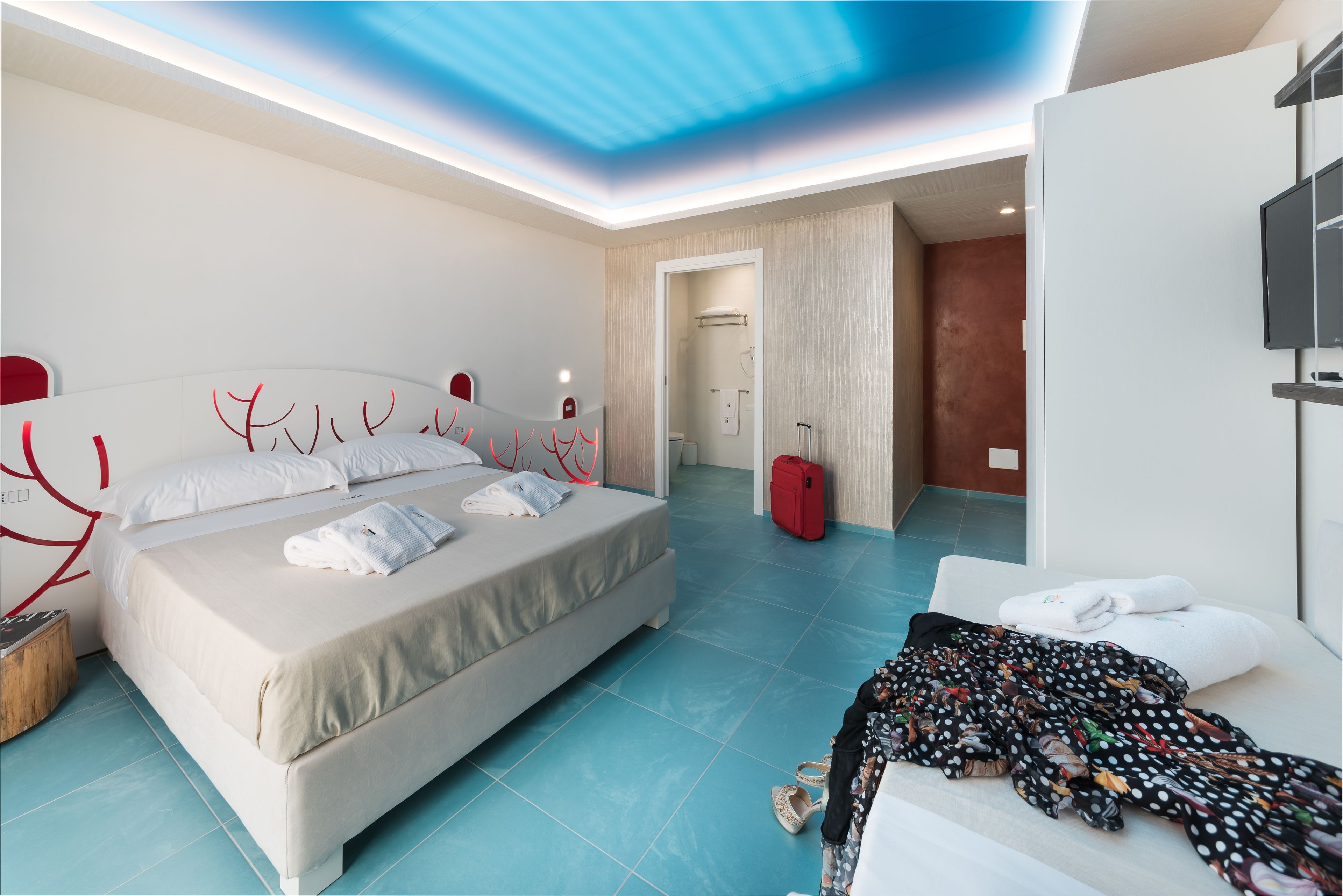 A modern hotel room with a large bed, a desk, and a TV.