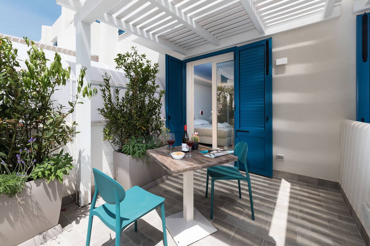 A small outdoor patio with a table, chairs, and potted plants.