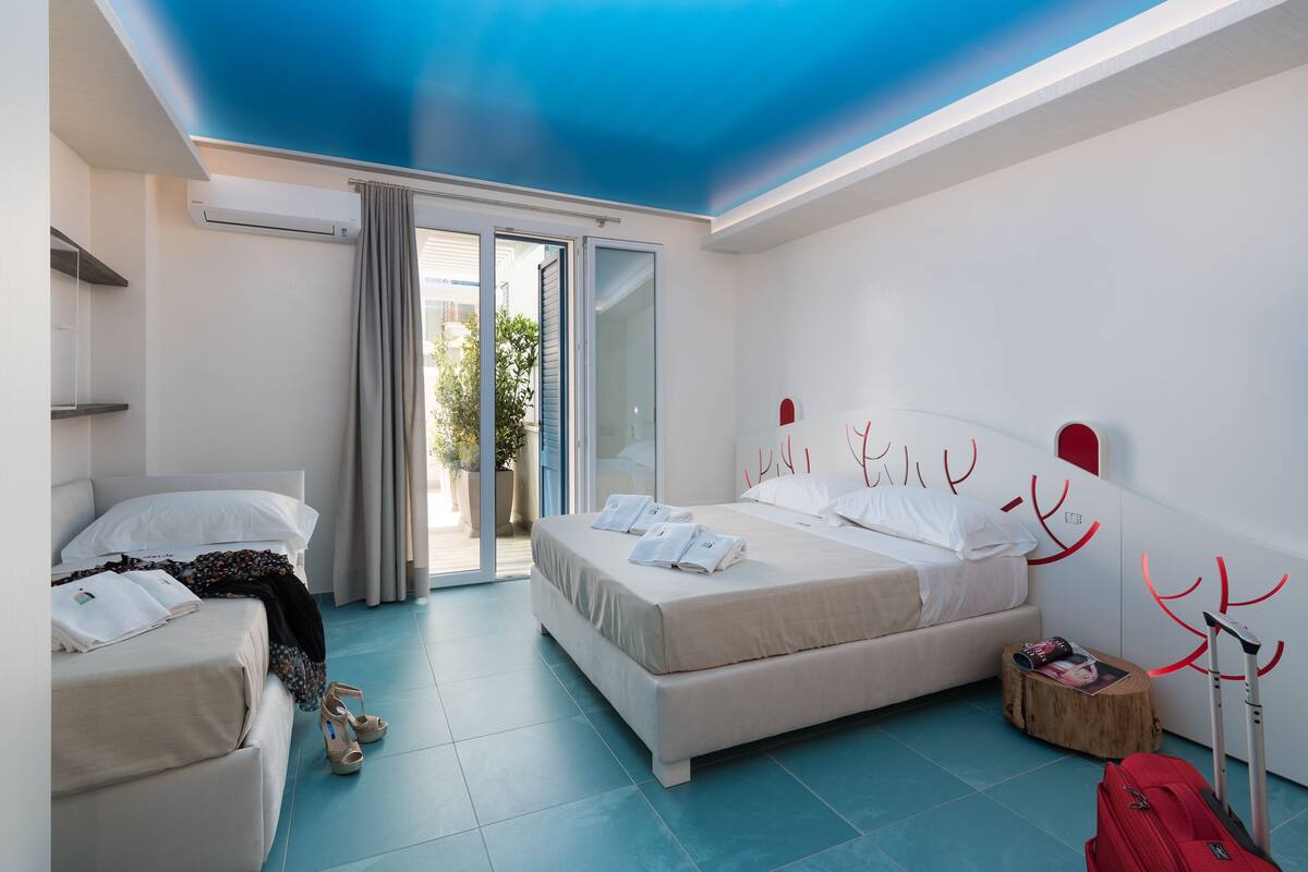 A bedroom with a bed, a suitcase, and a suitcase trolley.