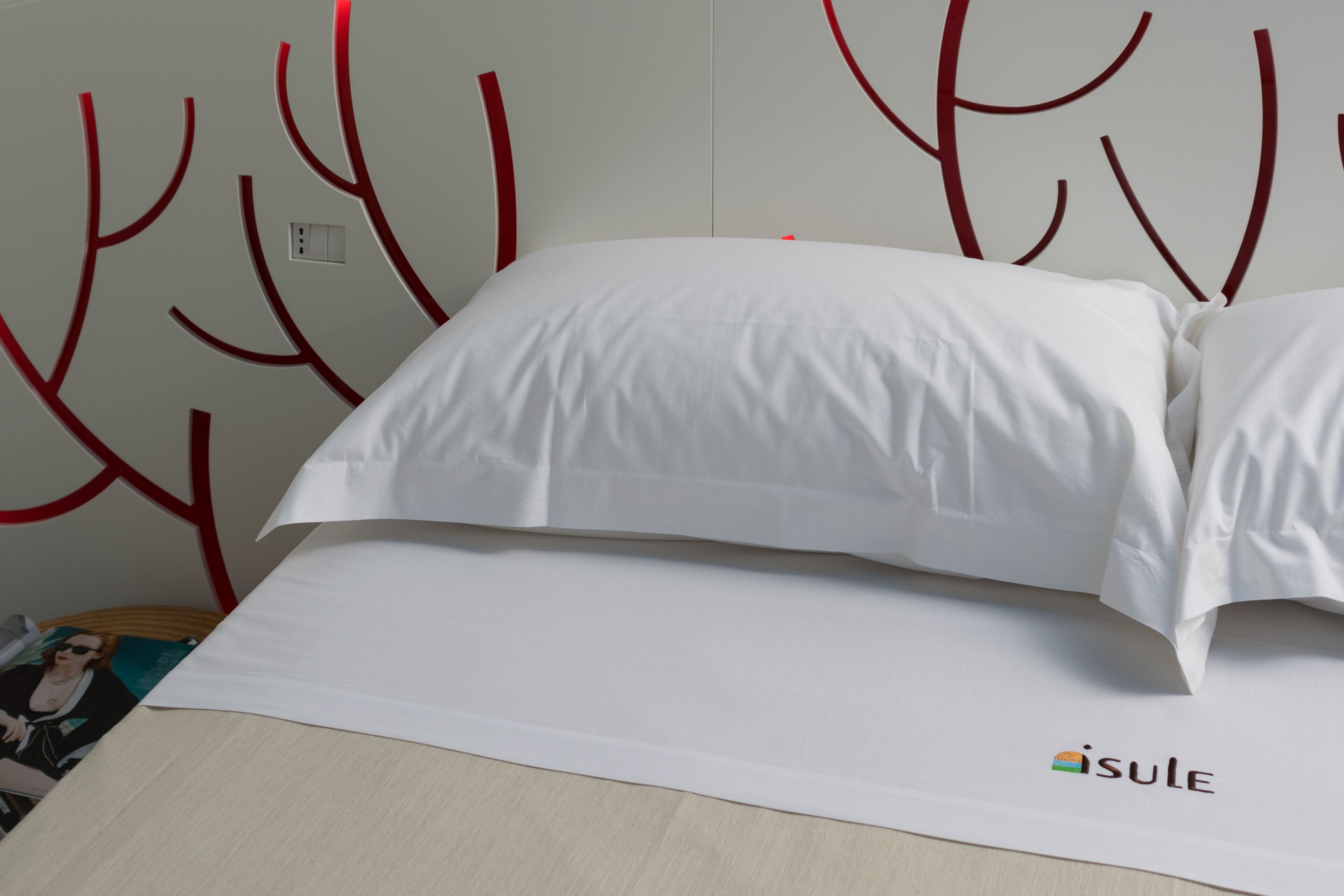 Una cama con ropa blanca y un logotipo en la sábana inferior.