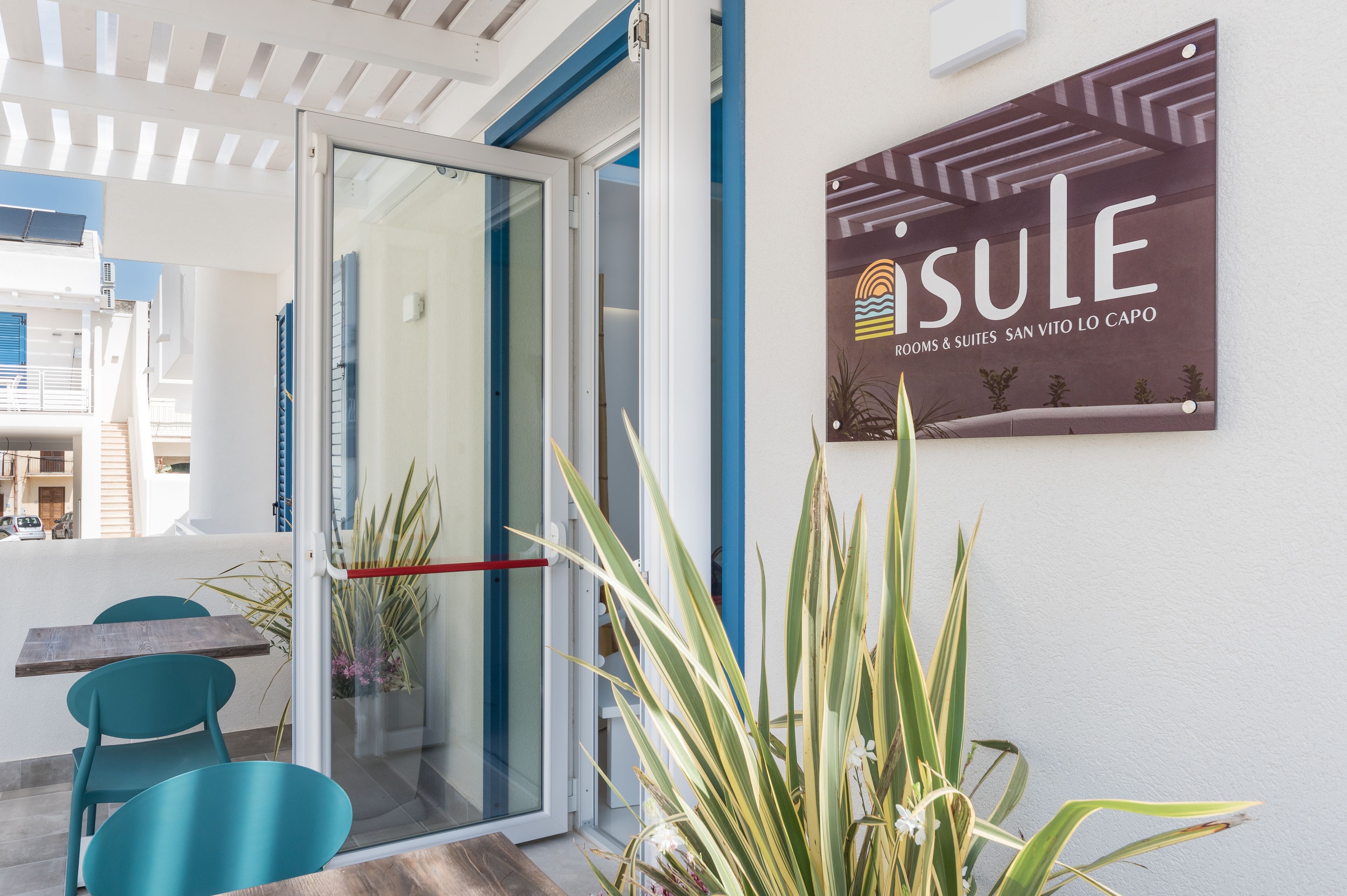 Ein Hotel mit Eingang, Glasdoor, Schild und einer kleinen Außenbereichssitzgelegenheit mit Stühlen und Tisch.