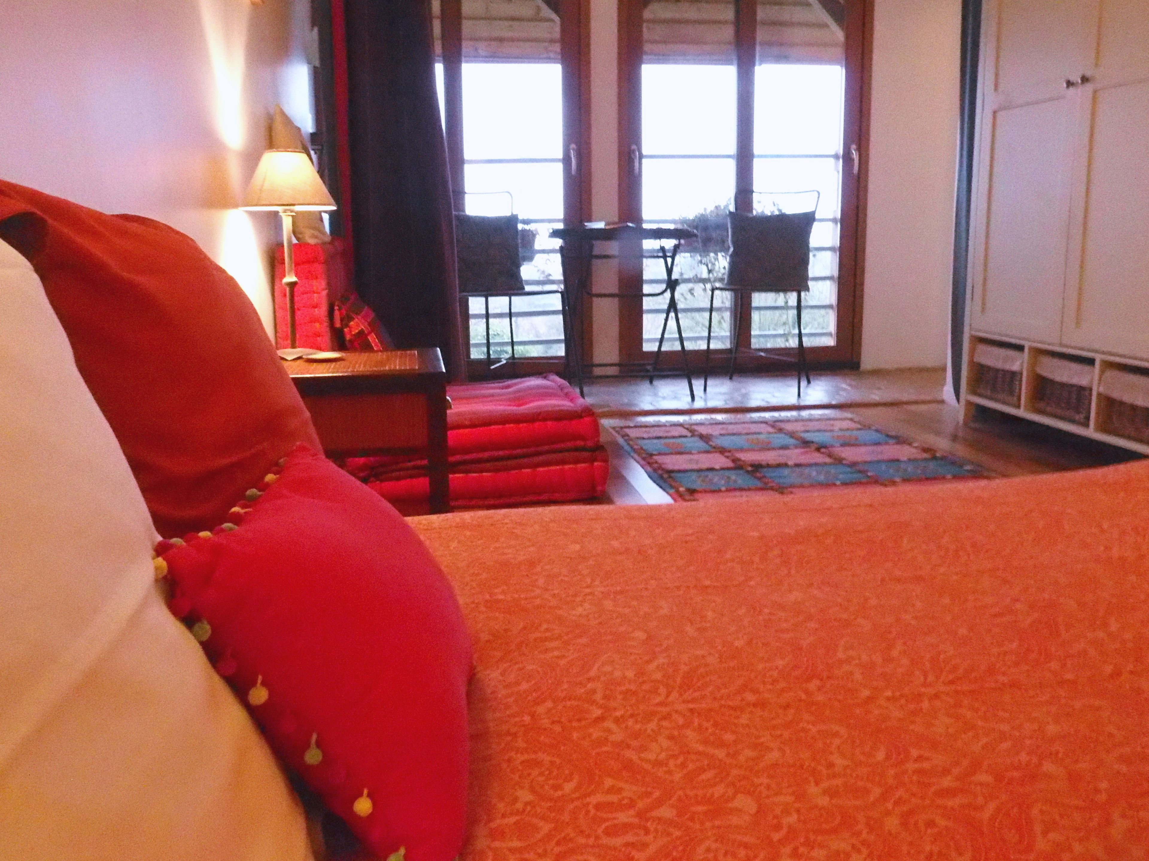 Habitación de hotel con cama, una silla, una mesa y vistas al exterior a través de un ventanal.