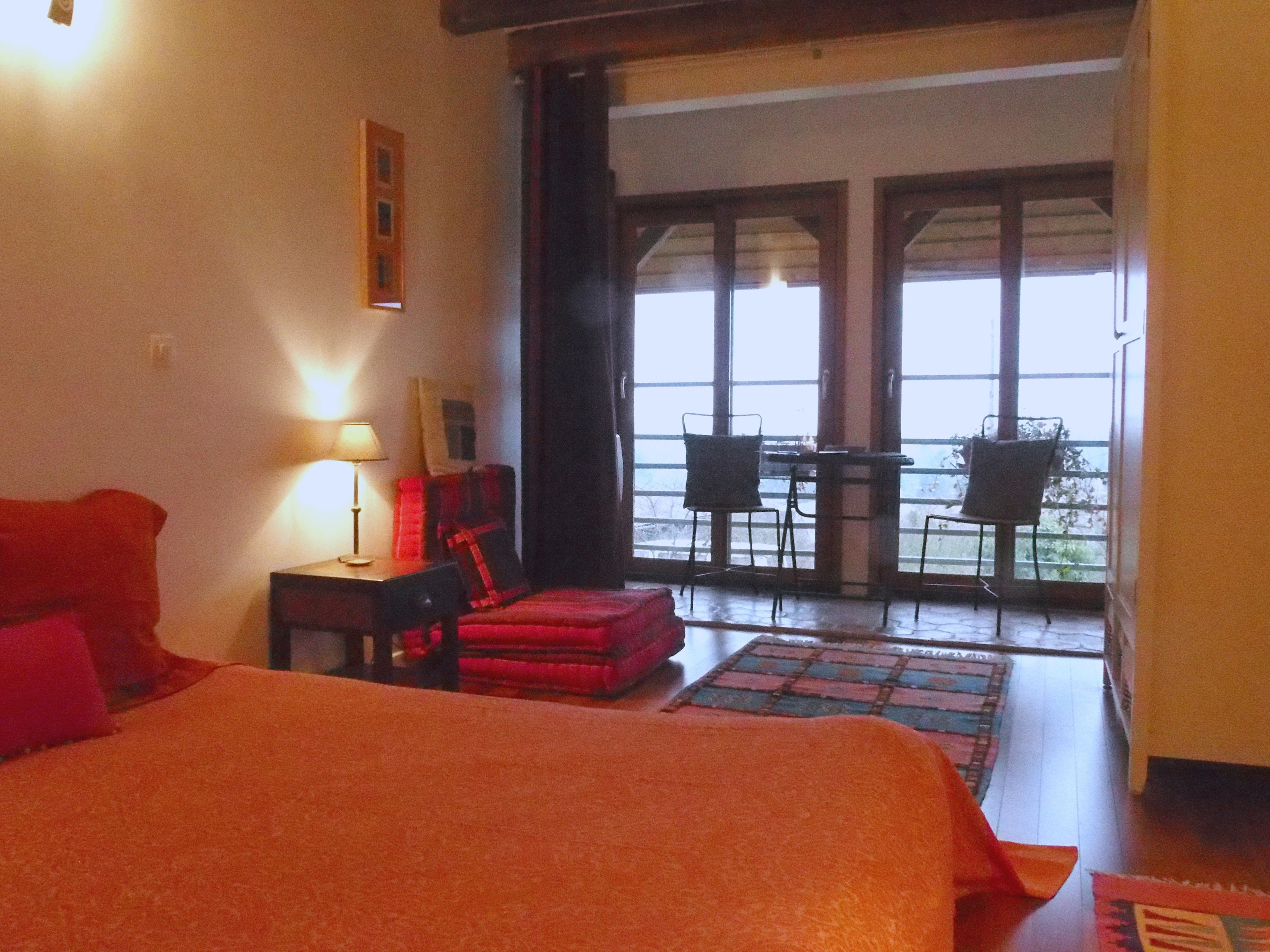 Une chambre d’hôtel comprenant un lit, un bureau avec une lampe, une chaise et un balcon avec une table et des chaises.