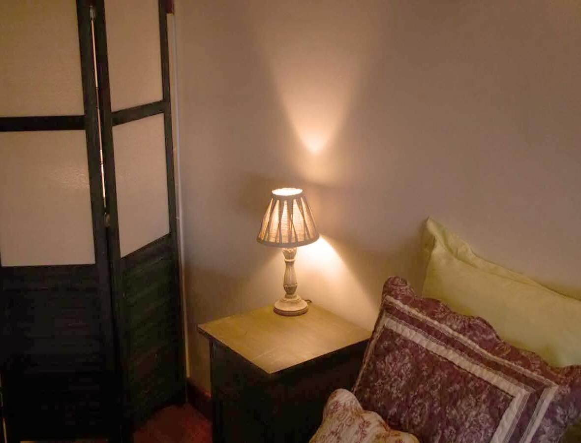 Une pièce avec un lit, une table de chevet avec une lampe et une porte qui est partiellement visible.
