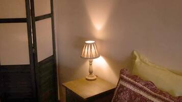 Une pièce avec un lit, une table de chevet avec une lampe et une porte qui est partiellement visible.