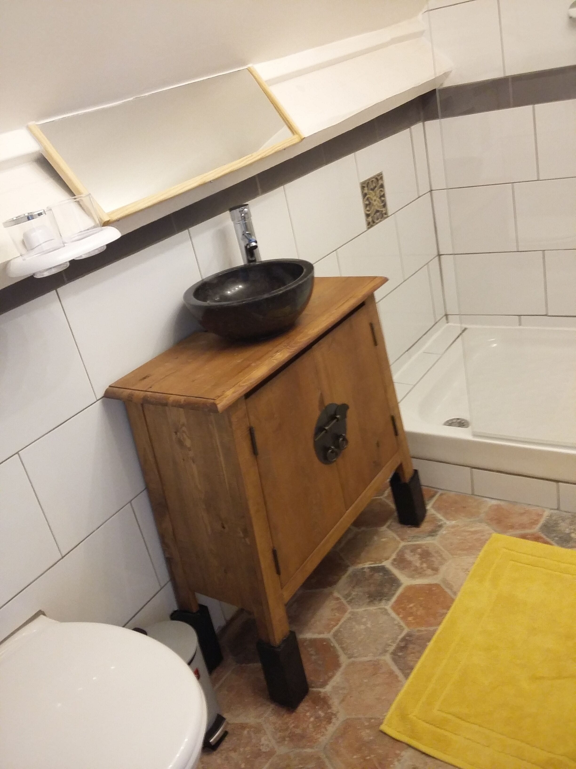 A bathroom with a wooden cabinet, a black sink, a white toilet, and a bathtub.