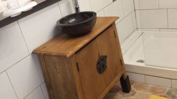 A bathroom with a wooden cabinet, a black sink, a white toilet, and a bathtub.