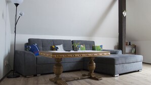A modern living room with a grey sofa, a wooden coffee table, and a tall floor lamp. - Red Point (Tabor)