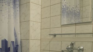 A bathroom with a white sink, a mirror, and a shower curtain with a cityscape design.
