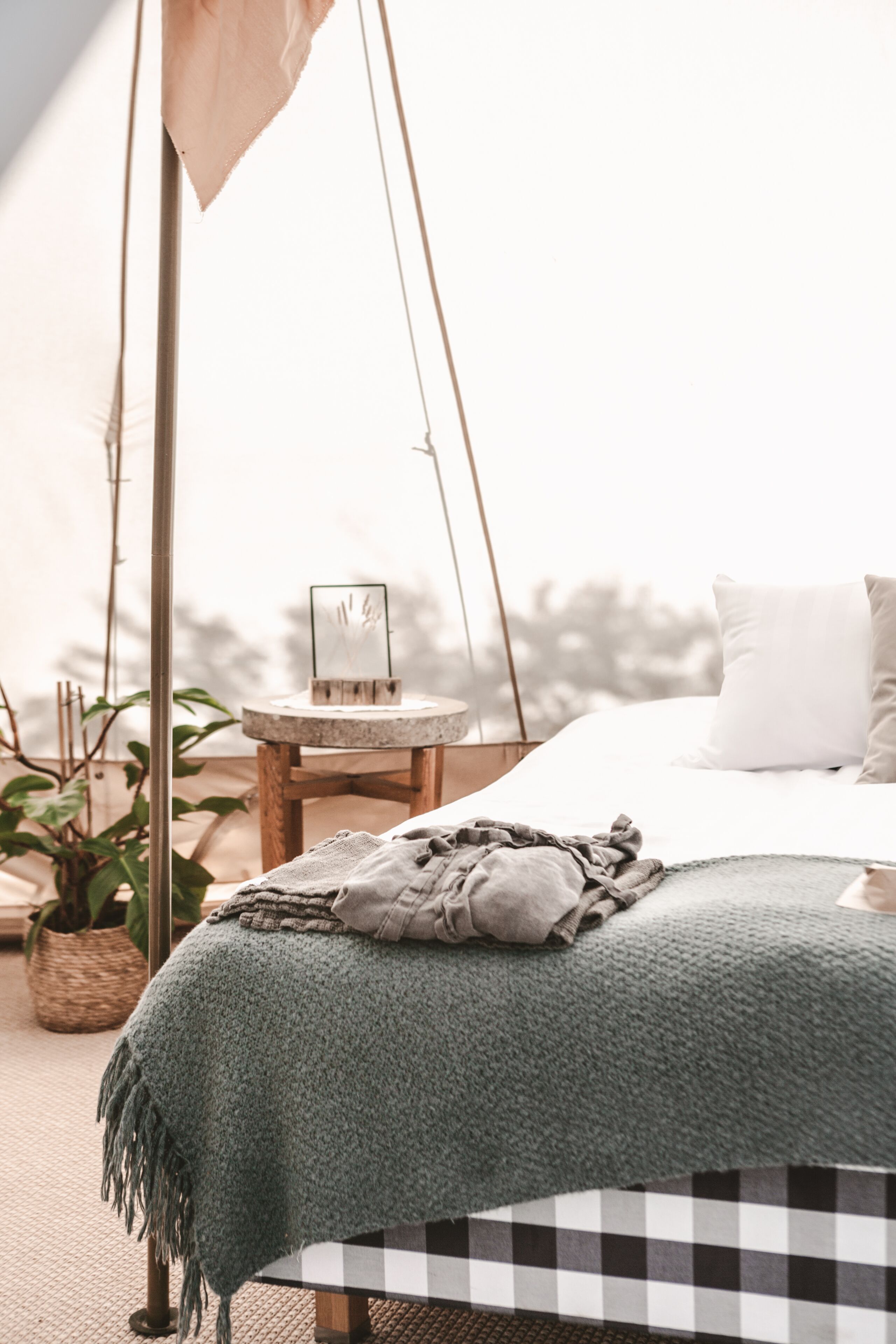 Un dormitorio acogedor con cama, una mesita redonda y una planta colgante.
