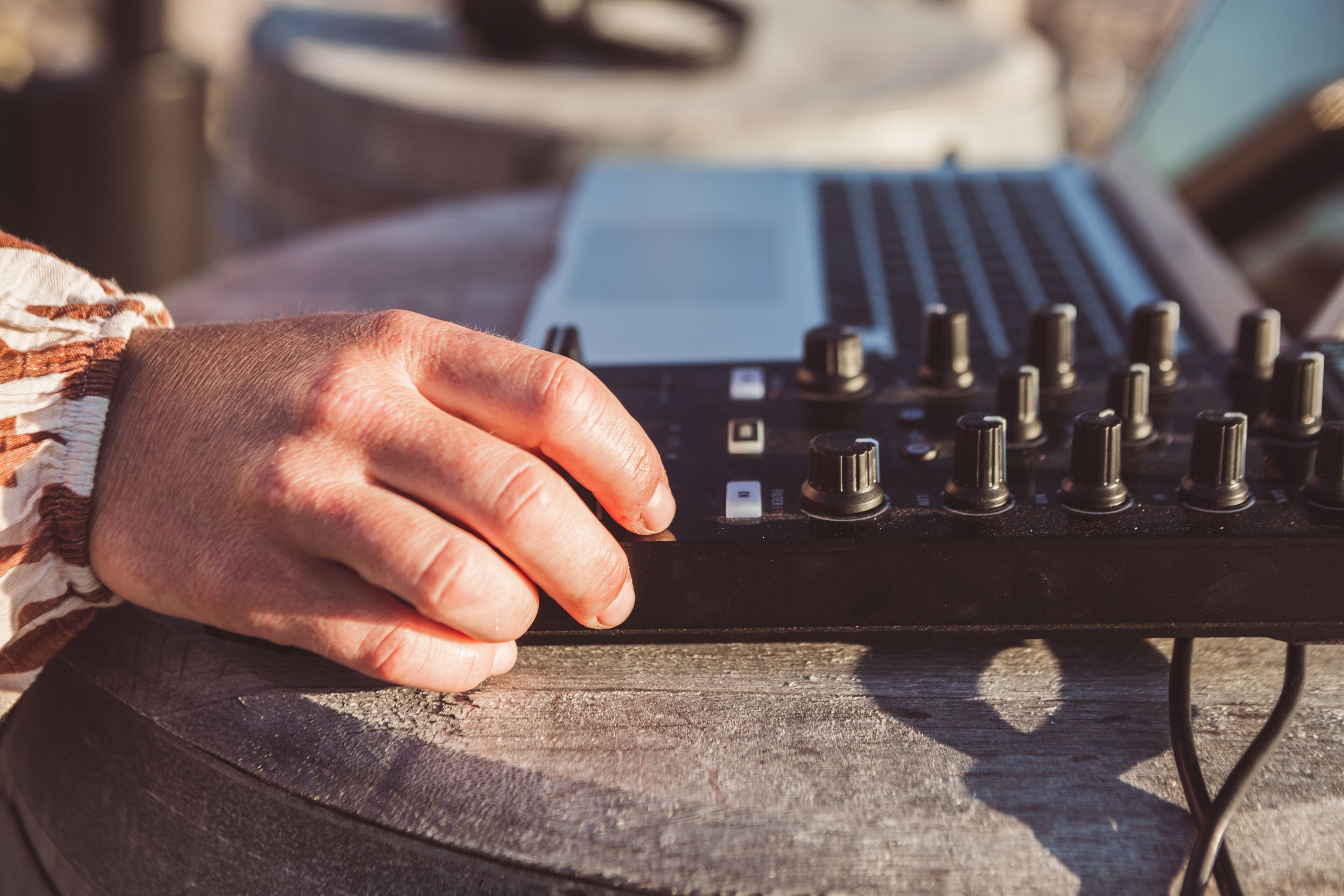 A hand adjusting knobs on a DJ mixer.