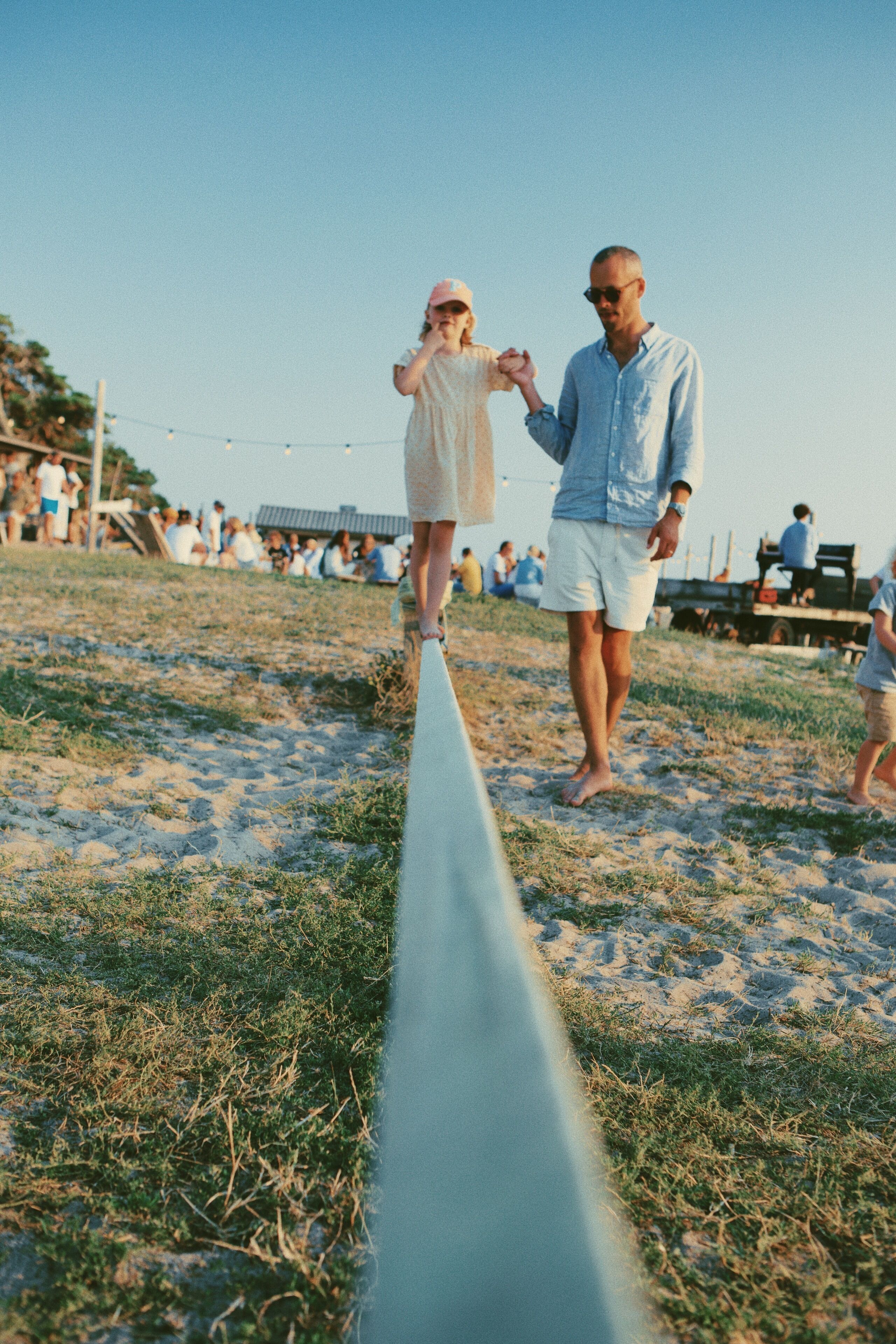 A beach scene with people walking on a rope.