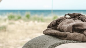 Una cama con una manta, una ventana y vista al mar.