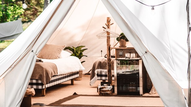 Una carpa con una cama, una mesita y un calentador en su interior.