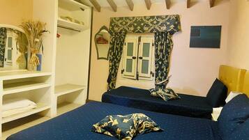 Un dormitorio con dos camas, un armario, una ventana con cortinas y un espejo.