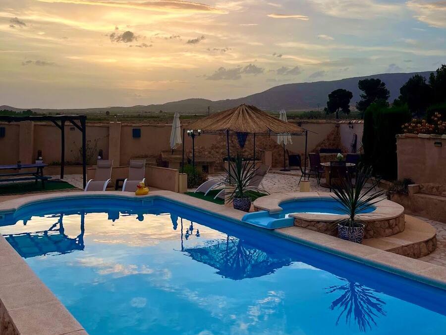 Una piscina al aire libre, sombrillas, sillones reclinables de piscina