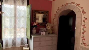A bedroom with a bed, dresser, mirror, and an arched doorway.