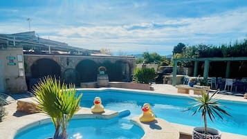 Een buitenzwembad, parasols bij het zwembad en ligstoelen