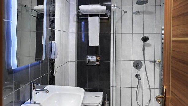 A modern bathroom with a white sink, toilet, and shower area. - Bent Hotel (Kocasinan)
