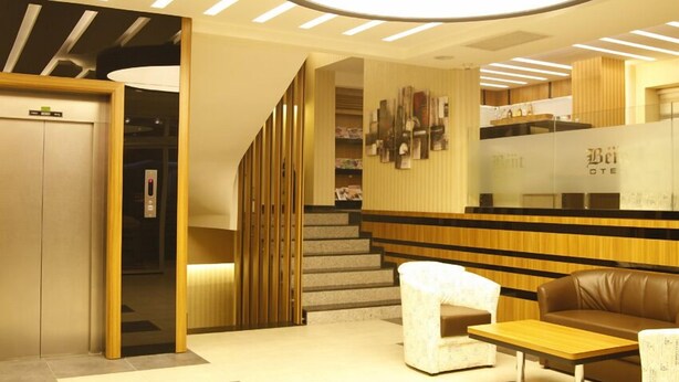 A modern hotel lobby with a reception desk, seating area, and an elevator. - Bent Hotel (Kocasinan)