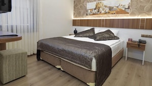 A modern hotel room with a large bed, a bedside table, a small desk, and a wall-mounted TV. - Bent Hotel (Kocasinan)