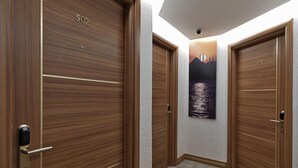 A hallway with three wooden doors, each marked with a number. - Bent Hotel (Kocasinan)